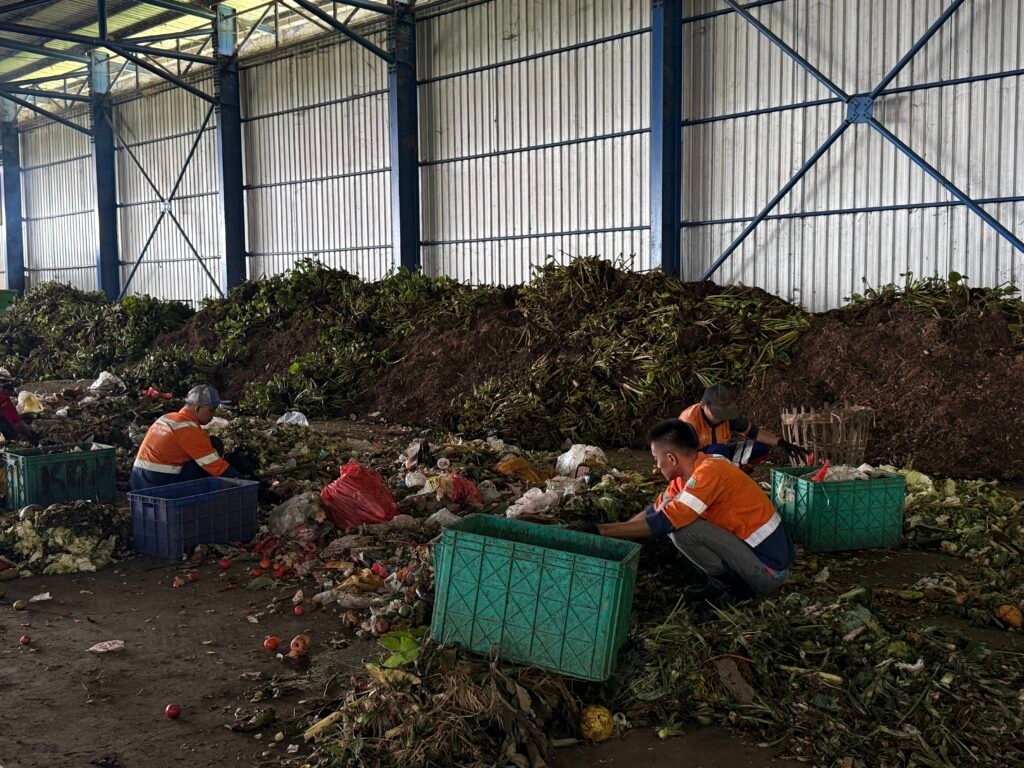 Pekerja memilah sampah organik di TPA Supit Urang, Kota Malang. Proses pemilahan ini menjadi tahap awal sebelum sampah diolah menjadi kompos, membantu mengurangi volume sampah yang berakhir di landfill.