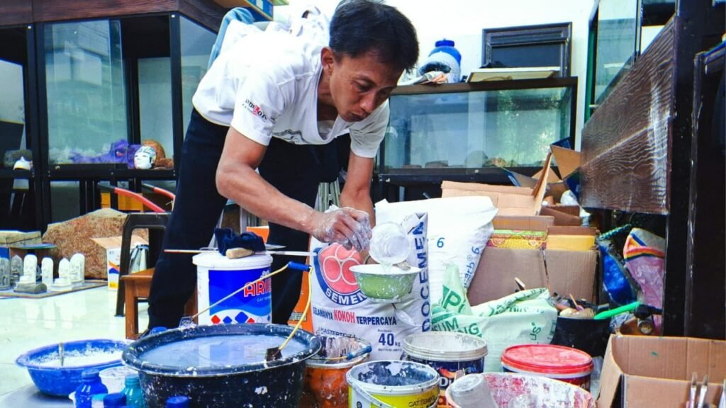 Salah satu penjaga Museum Singhasari mempraktekan cara membuat adonan bubur kertas untuk topeng malangan