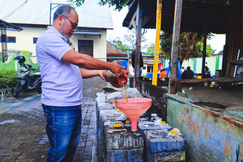 Hari Suprayitno atau yang dikenal sebagai Palim sedang menuangkan minyak jelantah ke dalam jeriken