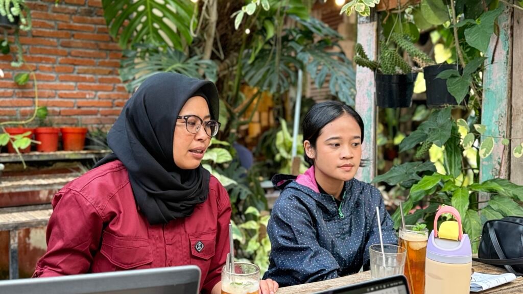 Koordinator Zona Bening sedang diwawancarai oleh tim liputan di area  cafe terbuka yang dipenuhi tanaman hijau di Kota Batu.