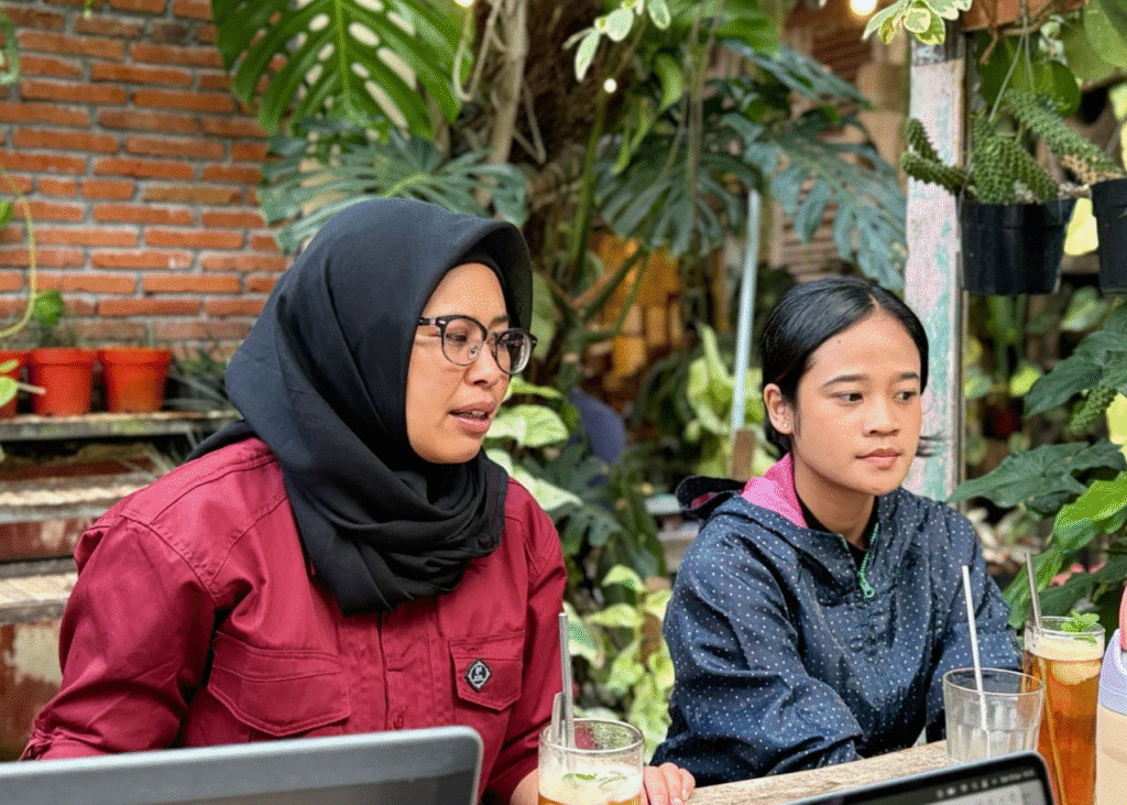 Koordinator Zona Bening sedang diwawancarai oleh tim liputan di area  cafe terbuka yang dipenuhi tanaman hijau di Kota Batu.
