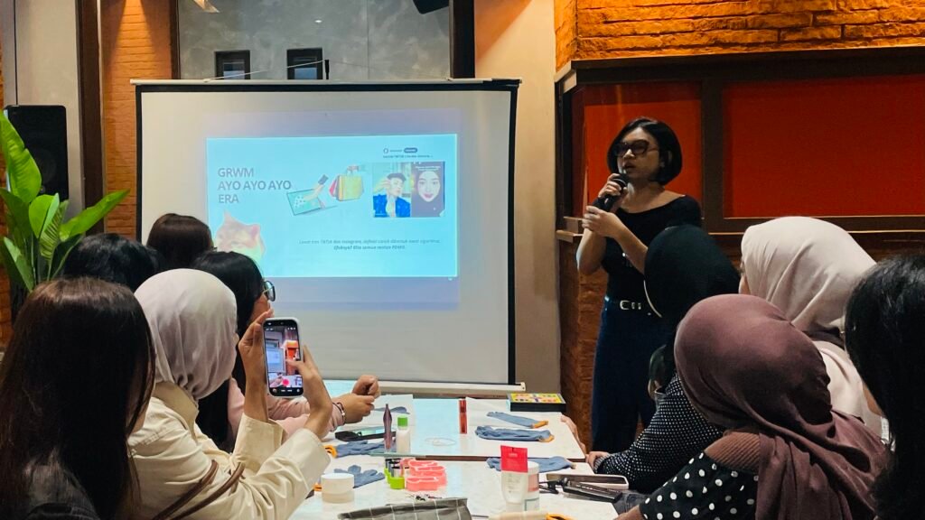 Seorang pemateri sedang menyampaikan materi di depan peserta workshop Beyond Beauty. Di layar proyektor ditampilkan presentasi tentang tren kecantikan dan media sosial, sementara peserta duduk memperhatikan penjelasan yang berlangsung di dalam ruangan.